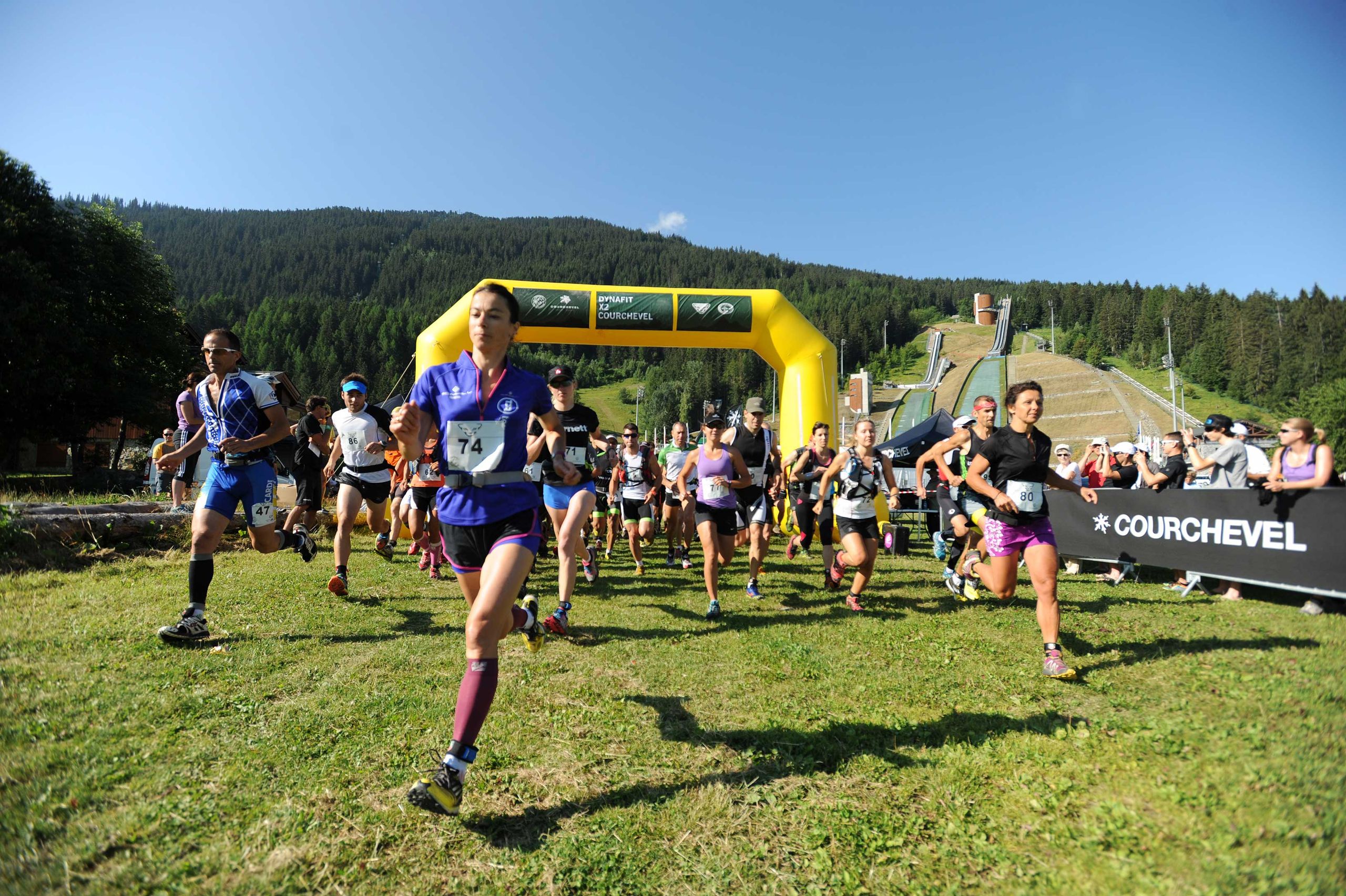 Runners at the start of a summer trail race, start arch behind
